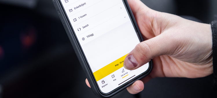 En människa sitter inne i en buss och har uppe appen Kalmar länstrafik.