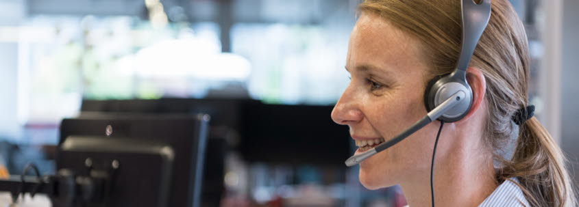 Kvinna med headset tittar på skärm.