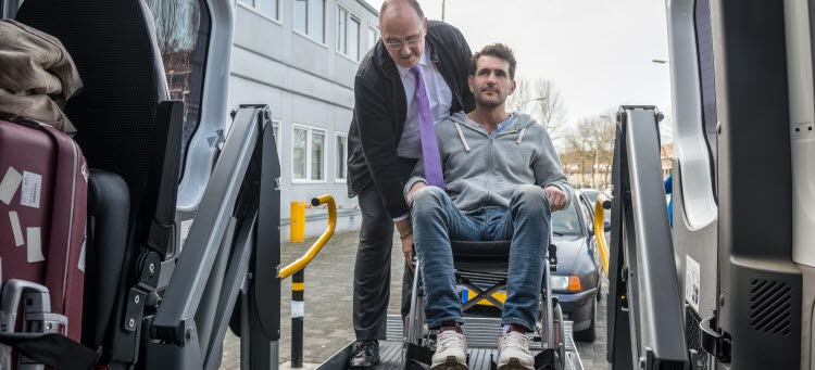 En förare hjälper en rullstolsburen man ombord på fordonet
