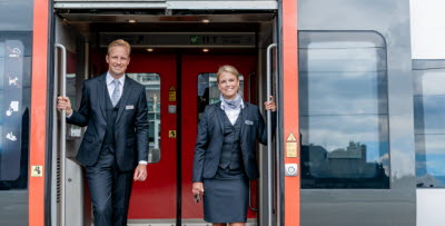 Två tågvärdar poserar i dörren till ett Öresundståg